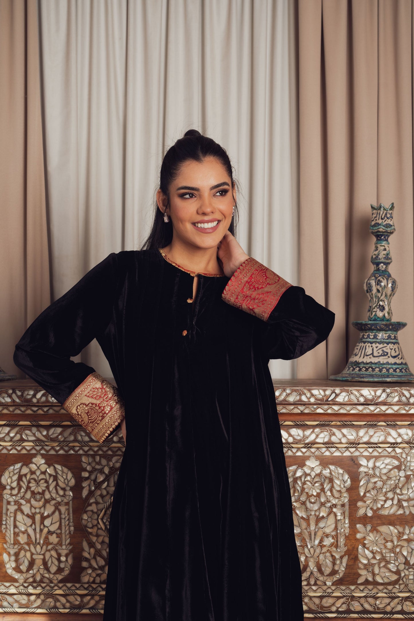 A timeless black velvet kaftan featuring intricate gold and red
