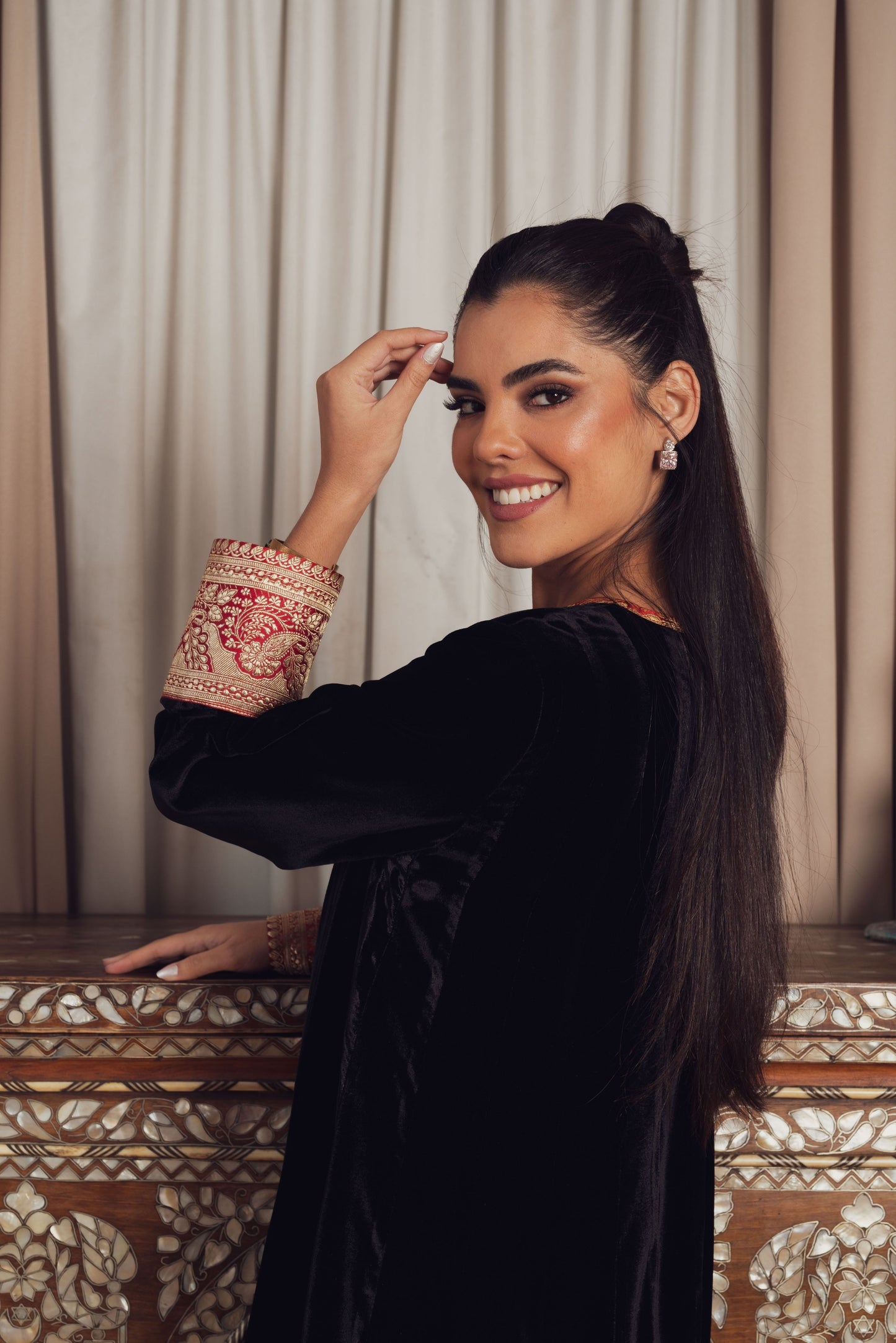 A timeless black velvet kaftan featuring intricate gold and red