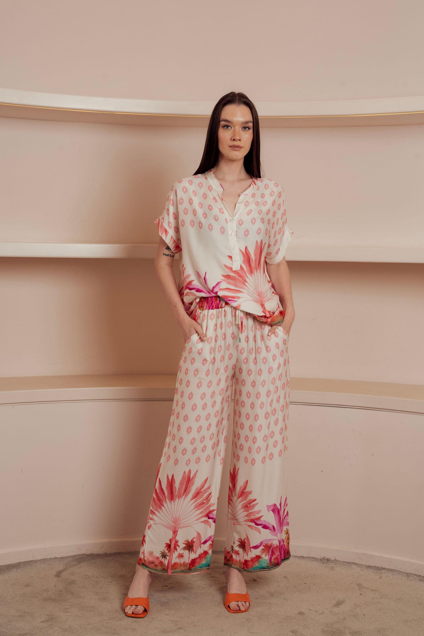 Light button-up blouse with a soft pink geometric pattern and tropical floral print at the hem.