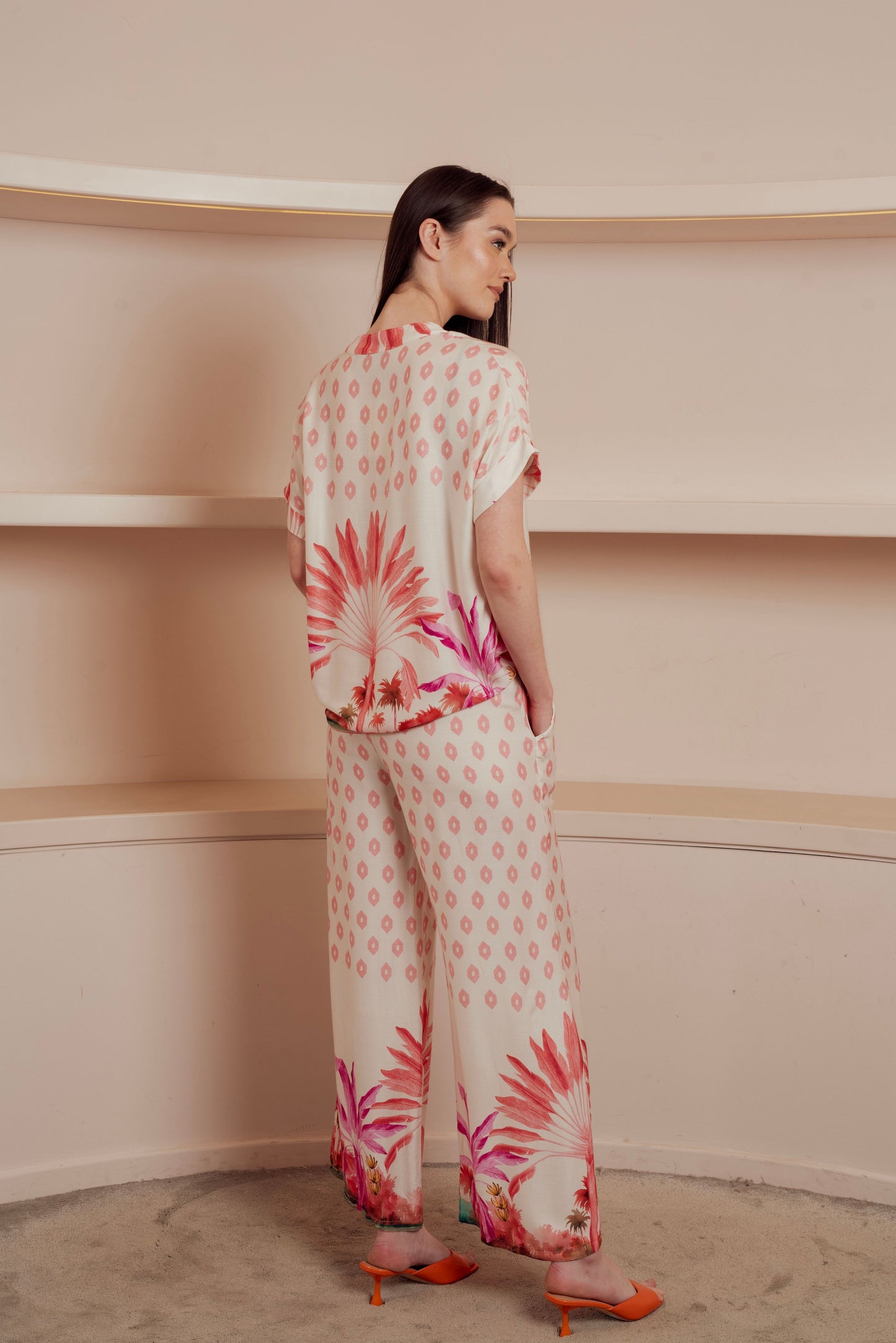 Light button-up blouse with a soft pink geometric pattern and tropical floral print at the hem.