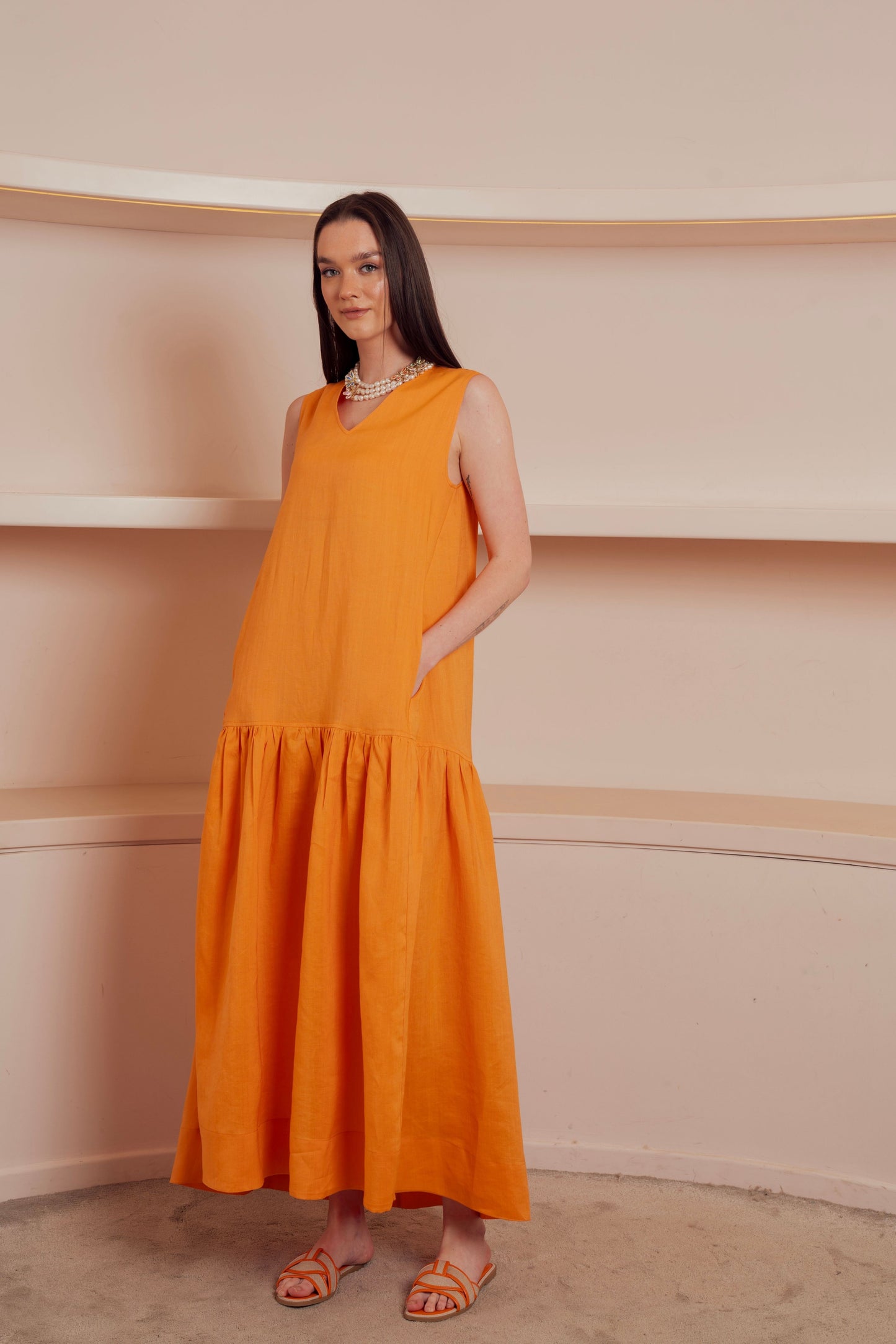 Sleeveless orange midi dress with drop waist.