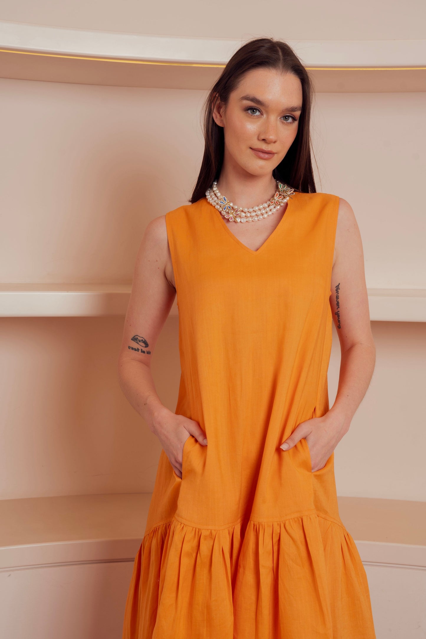 Sleeveless orange midi dress with drop waist.