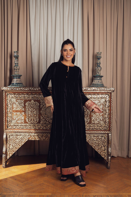 A timeless black velvet kaftan featuring intricate gold and red